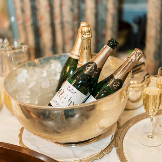 Three bottles of champagne sit in a silver ice bucket beside a pair of filled flutes, ready to toast a memorable evening at The Lanes.