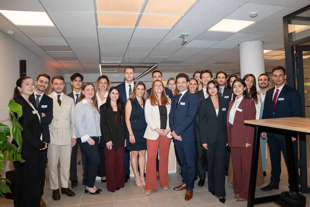 Un groupe de personnes habillées professionnellement pose ensemble pour une photo dans un bureau.