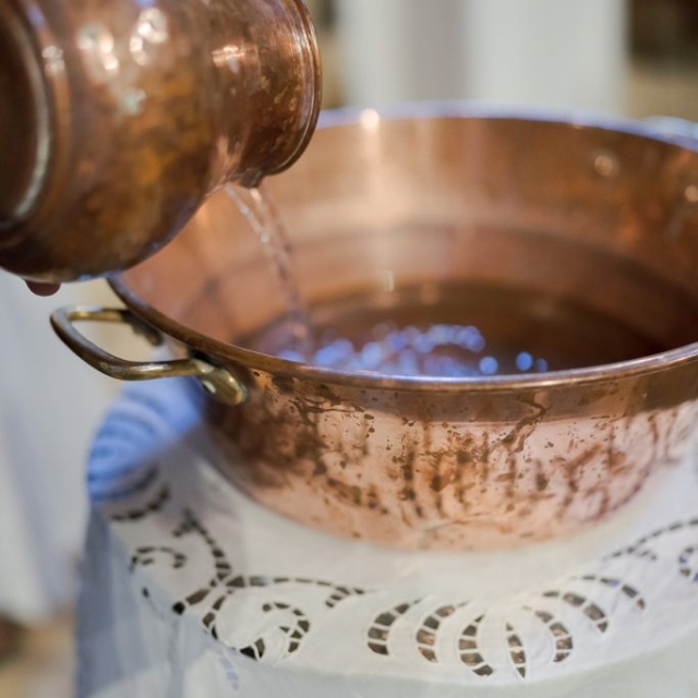 photographe-bapteme-Elisa-Design-Photography (27) A copper pitcher pours water into a large copper basin on a lace-covered table, evoking the serene ritual of baptism.